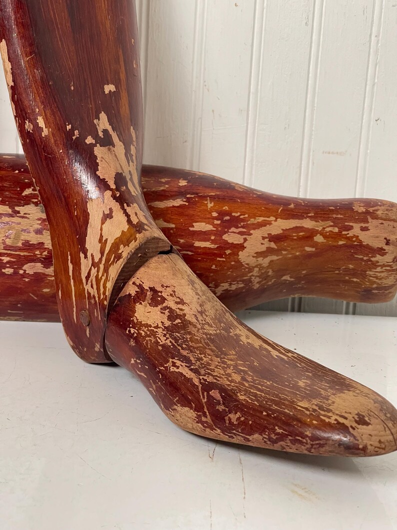 May include: A pair of vintage wooden shoe stretchers with a reddish-brown finish. The stretchers are worn and have a distressed look.