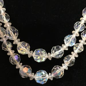 May include: A double strand necklace made of clear faceted glass beads. The beads are iridescent and reflect light.