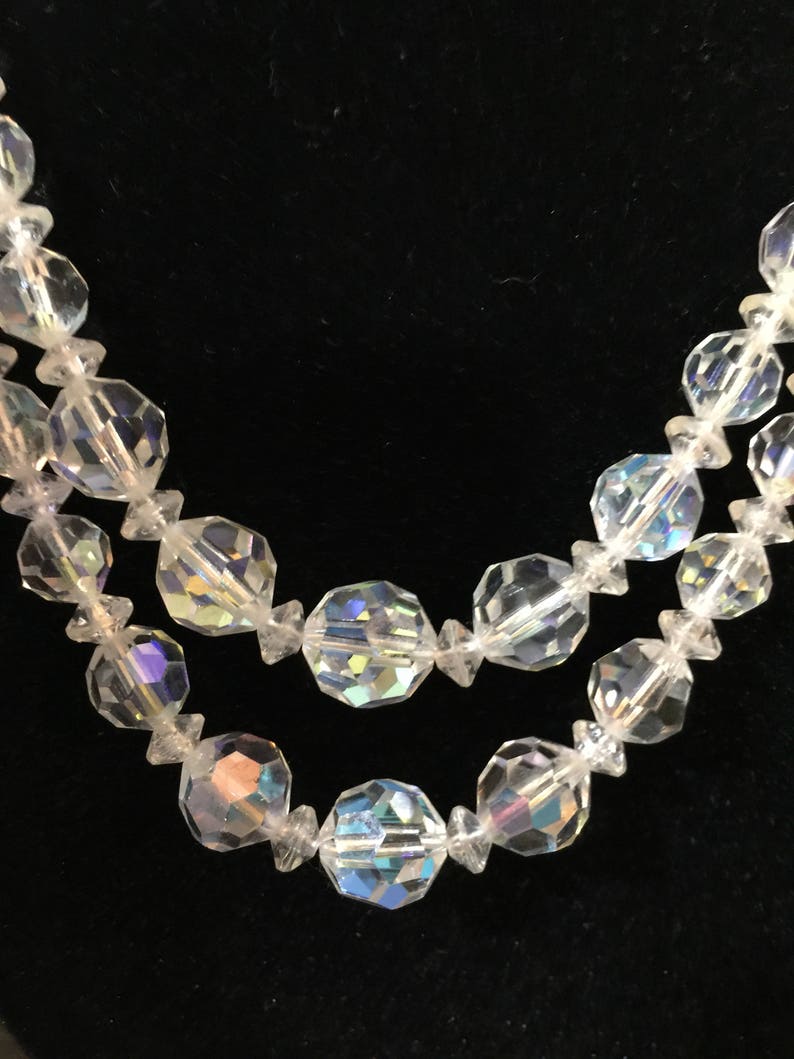 May include: A double strand necklace made of clear faceted glass beads. The beads are iridescent and reflect light.