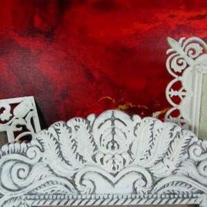 May include: Three white ornate picture frames with intricate designs. The frames are against a red background.
