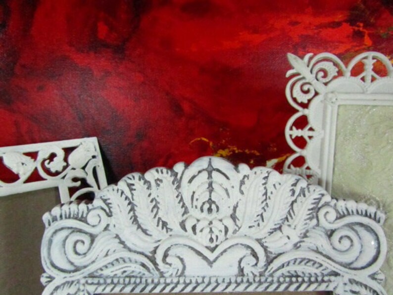 May include: Three white ornate picture frames with intricate designs. The frames are against a red background.