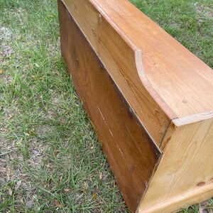 K&ouml;nnte beinhalten: Eine Holzaufbewahrungsbank mit einem Klappdeckel und einer nat&uuml;rlichen Holzoptik. Die Bank ist aus massivem Holz gefertigt und hat ein schlichtes, rustikales Design.