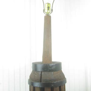 May include: A vintage wooden lamp base made from a repurposed wagon wheel. The lamp has a black metal shade and a simple metal lampshade holder. The lamp is approximately 24 inches tall.