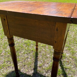 May include: A wooden side table with a warm, brown finish. The table has a rectangular top and four turned legs. The table is approximately 30 inches long, 18 inches wide, and 28 inches tall.