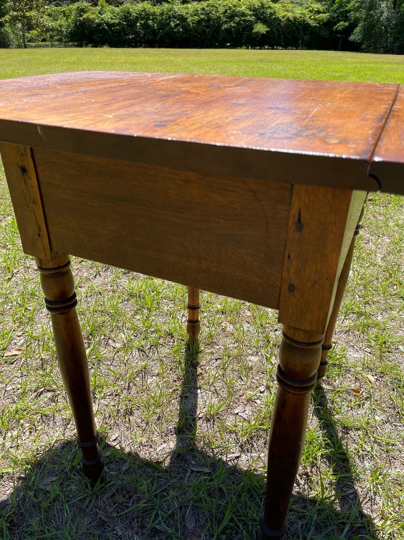 May include: A wooden side table with a warm, brown finish. The table has a rectangular top and four turned legs. The table is approximately 30 inches long, 18 inches wide, and 28 inches tall.