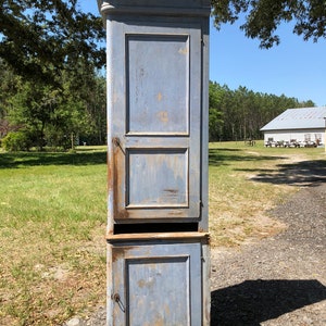 May include: A tall, blue, wooden cabinet with two doors. The cabinet has a distressed finish and is in good condition.
