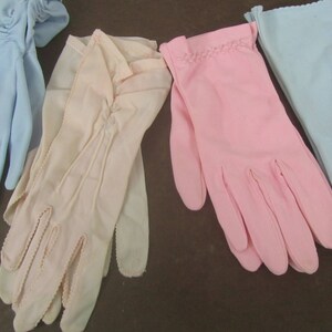 May include: Four pairs of gloves in different colors: light blue, pink, and two shades of beige. The gloves are made of a soft, delicate fabric and have a classic, elegant style.