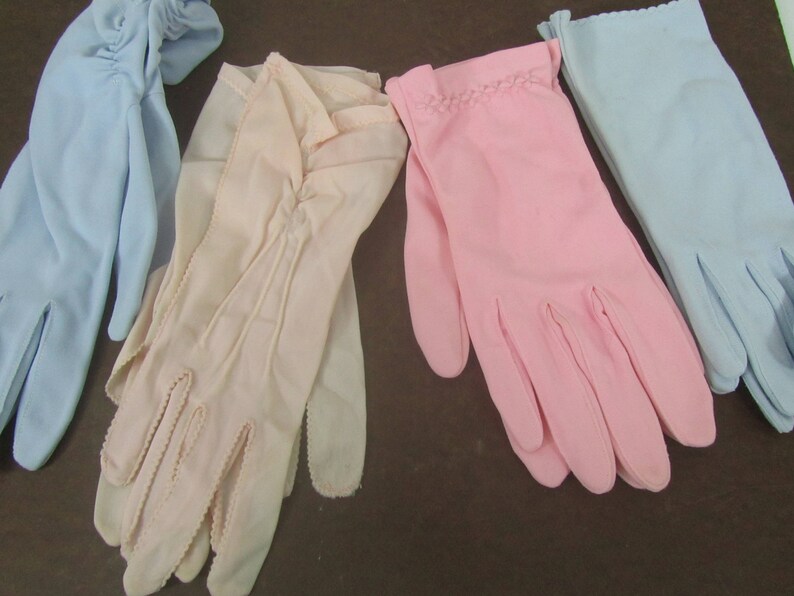 May include: Four pairs of gloves in different colors: light blue, pink, and two shades of beige. The gloves are made of a soft, delicate fabric and have a classic, elegant style.