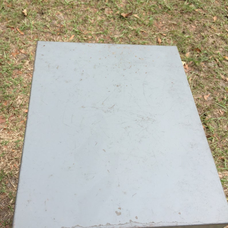 May include: A gray metal box with scratches and marks on the surface.