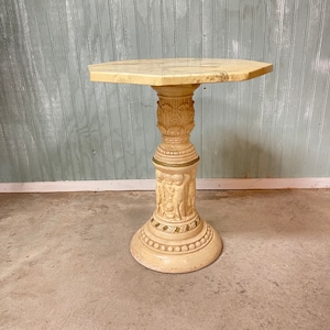 May include: A white octagonal side table with a carved base featuring cherubs and gold accents. The table top is made of marble.