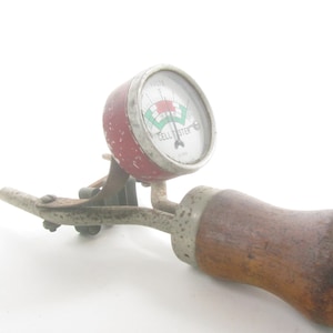 May include: Vintage red and white cell tester with a wooden handle. The gauge reads "CELL TESTER" and has a green and red needle.