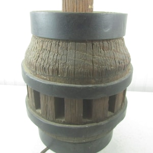 May include: A vintage wooden spoked wheel with a black metal rim. The wheel is mounted on a wooden post.