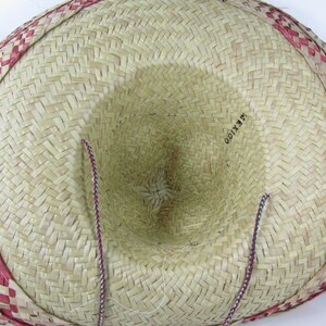 May include: A straw sombrero with a red and white checkered band around the brim. The hat has a brown and white string attached to the inside.