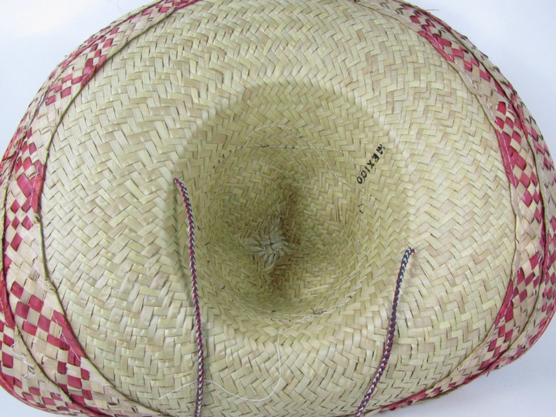 May include: A straw sombrero with a red and white checkered band around the brim. The hat has a brown and white string attached to the inside.