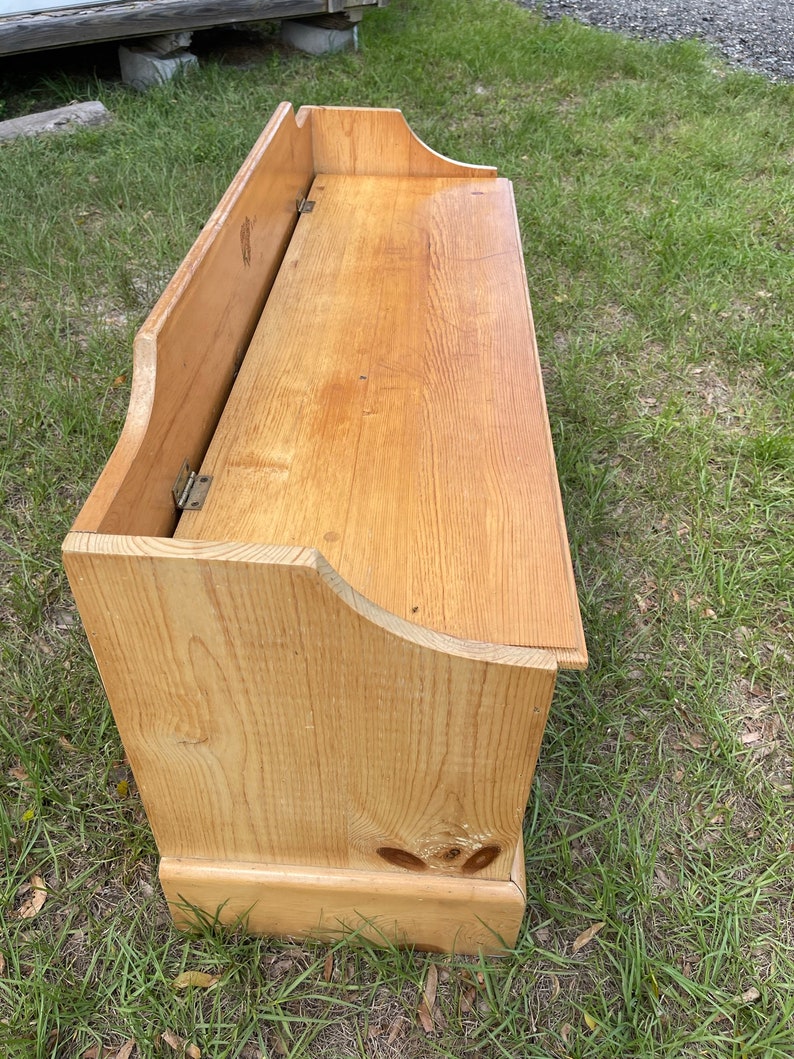 K&ouml;nnte beinhalten: Eine Holz-Aufbewahrungsbank mit einer Klappdeckel. Die Bank ist aus hellem Holz und hat ein schlichtes Design.