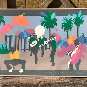 Puede incluir: Una impresi&oacute;n colorida y abstracta de una escena callejera de Nueva Orleans con una banda de m&uacute;sica, palmeras y personas que sostienen paraguas. La impresi&oacute;n est&aacute; enmarcada en un marco rosa claro.