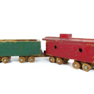 May include: A vintage wooden toy train with a green boxcar and a red caboose. The train has wooden wheels and is painted in a rustic style.