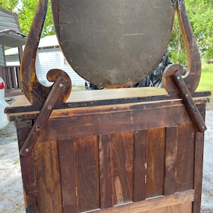Puede incluir: Espejo de tocador antiguo de madera con un espejo ovalado biselado y un marco de madera tallada ornamentado. El espejo est&aacute; unido a un gabinete de madera con una puerta con bisagras.