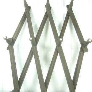 May include: A wooden coat rack with six hooks, in a diamond pattern, painted in a dark brown color.