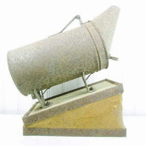 May include: A vintage metal bee smoker with a bellows and a metal nozzle. The smoker is rusty and has a brown leather bellows.