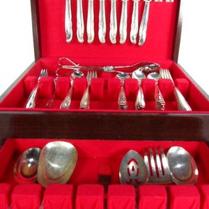 May include: A wooden box with a red velvet interior, containing a set of silverware. The silverware is arranged in rows and includes forks, knives, spoons, and serving utensils.