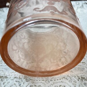 May include: A clear glass vase with a pink floral design. The vase has a round base and a wide opening.