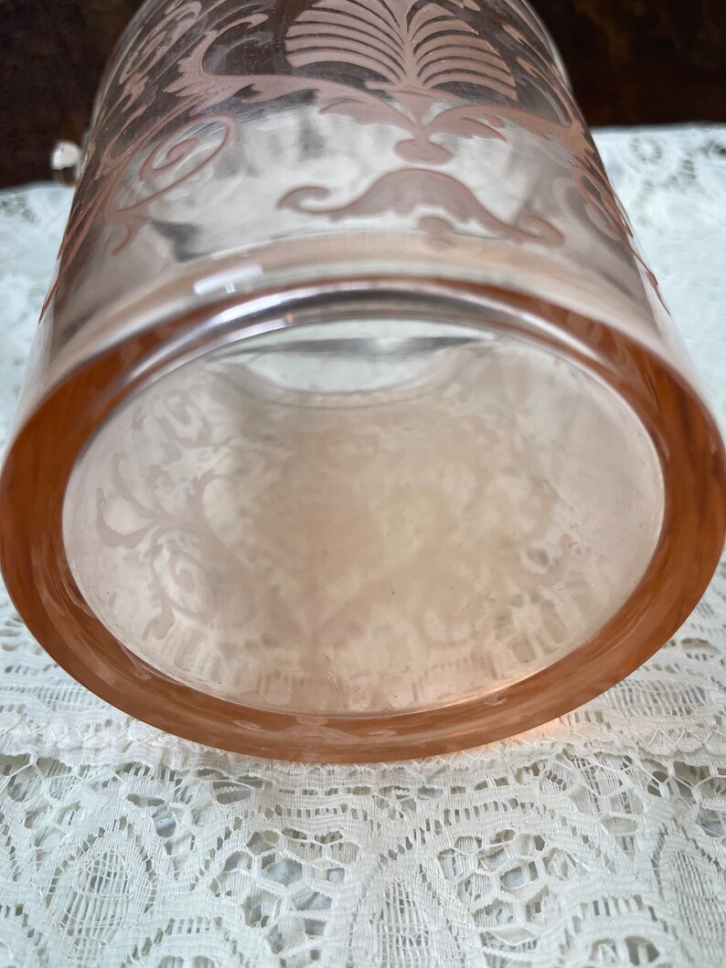 May include: A clear glass vase with a pink floral design. The vase has a round base and a wide opening.