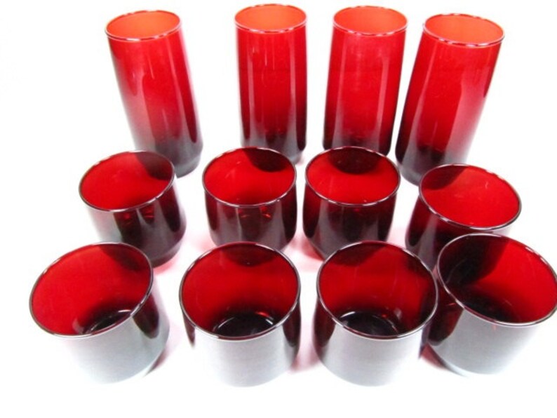 May include: Set of 12 red glass tumblers, some tall and some short. The glasses are all a deep red colour and have a smooth, rounded shape.