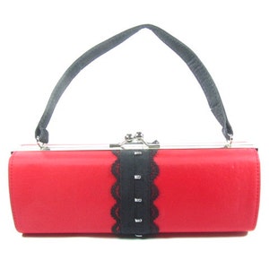 May include: A red satin clutch bag with a black lace trim and a silver clasp. The bag has a black strap.