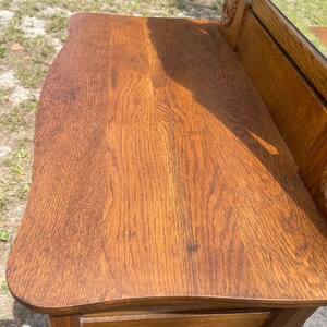 May include: A vintage wooden vanity with a curved top and three drawers. The vanity is made of dark wood with a rich brown finish. The vanity has a mirror on the top, which is not visible in the image.