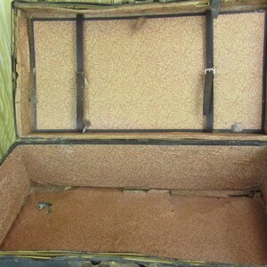 May include: An antique wooden trunk with a brown leather exterior and a floral patterned lining. The trunk is open and empty.