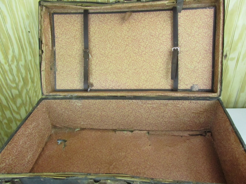May include: An antique wooden trunk with a brown leather exterior and a floral patterned lining. The trunk is open and empty.