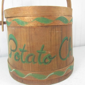 May include: A wooden bucket with a green painted handle and a green painted design around the top and bottom. The bucket is labeled "Potato Chips" in green paint.