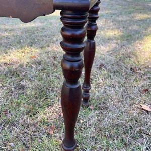 May include: Close-up of the turned legs of a dark brown wooden table. The legs are round and have a decorative design.