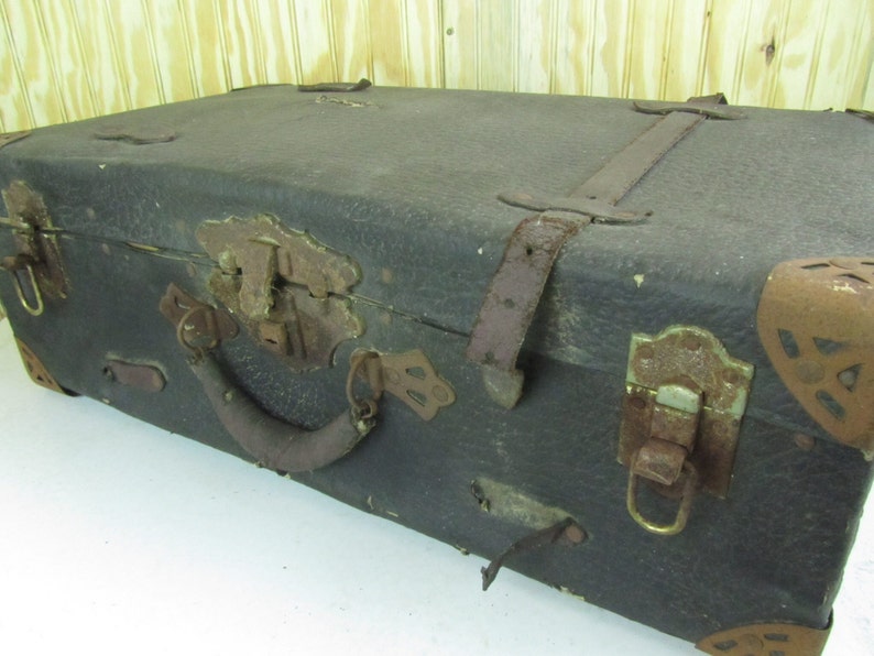 May include: A vintage, dark brown leather suitcase with metal hardware and a leather handle. The suitcase has a worn and weathered look, with signs of age and use.