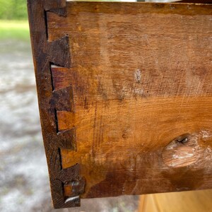 Puede incluir: Primer plano de un caj&oacute;n de madera con una uni&oacute;n de cola de milano. El caj&oacute;n est&aacute; hecho de madera marr&oacute;n claro y tiene un peque&ntilde;o agujero en la parte delantera.
