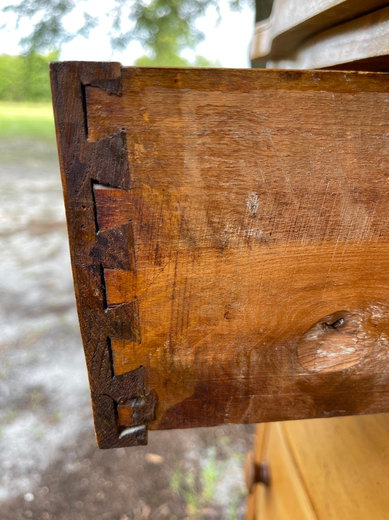 Puede incluir: Primer plano de un caj&oacute;n de madera con una uni&oacute;n de cola de milano. El caj&oacute;n est&aacute; hecho de madera marr&oacute;n claro y tiene un peque&ntilde;o agujero en la parte delantera.