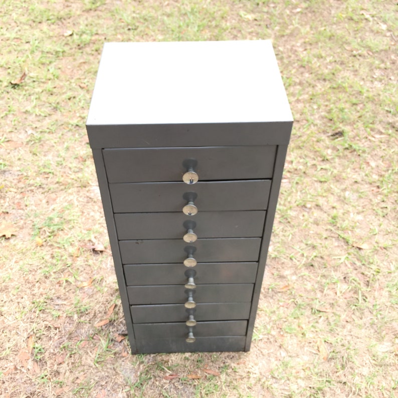May include: A dark gray metal drawer unit with eight drawers and silver knobs.