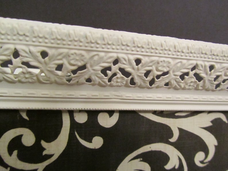 Puede incluir: Bandeja de metal blanco con un dise&ntilde;o floral decorativo alrededor del borde. La bandeja est&aacute; sobre una superficie con un patr&oacute;n blanco y negro.