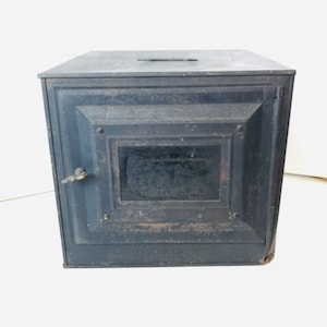 May include: Black cast iron wood-burning stove with a glass door and a single handle. The stove has a simple design and is in good condition.