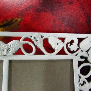 May include: White metal picture frame with a decorative design of hearts and leaves. The frame has a distressed white finish.