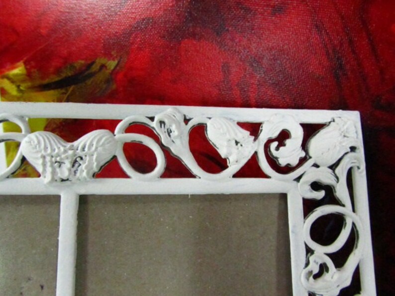 May include: White metal picture frame with a decorative design of hearts and leaves. The frame has a distressed white finish.