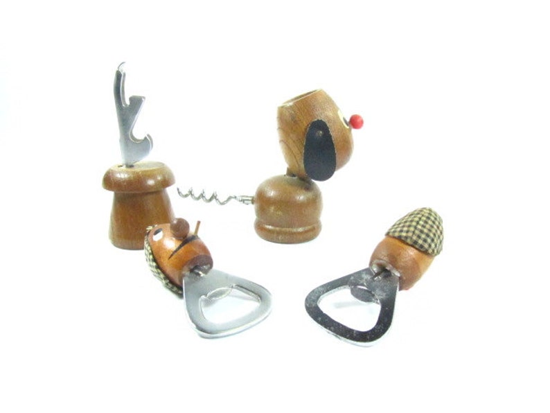 May include: A collection of wooden bottle openers and corkscrews. One opener is shaped like a dog with a red nose and black ear. Another has a mushroom-shaped base with a silver opener. The other two have a hat-shaped top.