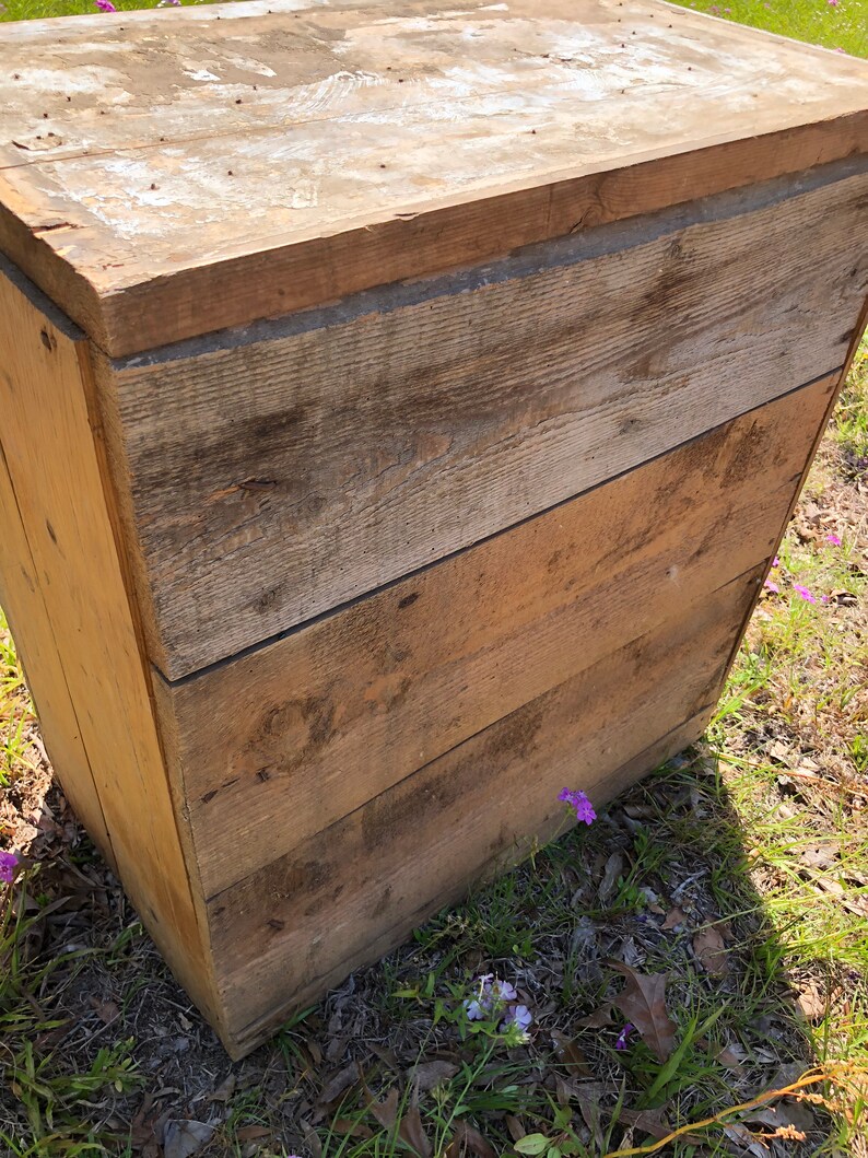 May include: A wooden storage box with a rustic, weathered finish. The box has a hinged lid and is made of natural wood planks.