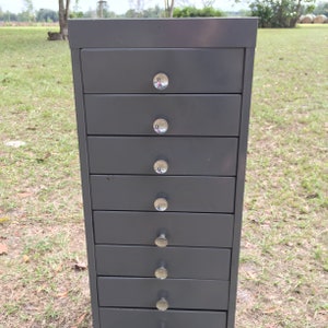 May include: A dark gray metal file cabinet with eight drawers and silver knobs.