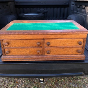May include: A wooden chest with four drawers and a green felt top. The chest has a traditional design with rounded edges and decorative details.
