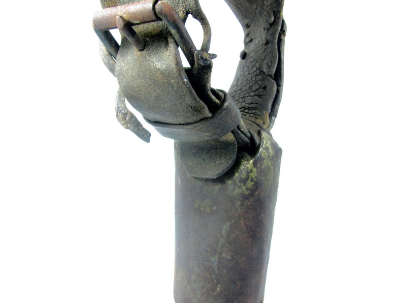 May include: A close-up of a vintage cowbell with a leather strap and buckle. The bell is made of metal and has a worn, rustic appearance.