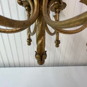 Pode incluir: Um candeeiro de teto de metal dourado com uma coluna central torcida e v&aacute;rios bra&ccedil;os, cada um terminando em um design floral decorativo.