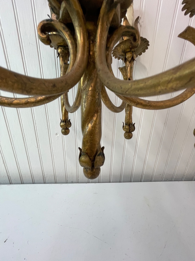 Pode incluir: Um candeeiro de teto de metal dourado com uma coluna central torcida e v&aacute;rios bra&ccedil;os, cada um terminando em um design floral decorativo.