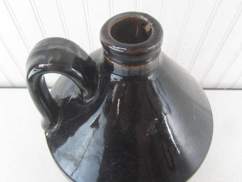 May include: A black glazed ceramic jug with a wide mouth and a handle. The jug has a smooth, shiny finish.